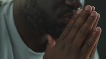 Close-Up of African American Man Praying with Hands Together
