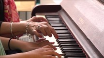 Woman teaching girl to play the piano