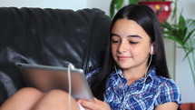 Smiling girl listening to music holding a tablet pc in hands