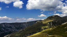 Transylvania Romania mountains landscape time lapse. Fast motion. Clouds are moving close to the mountain top. Green meadows and trees, blue sky.
