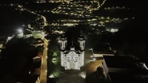 Drone orbits to the left around Church of Saint Francis of Assisi at night