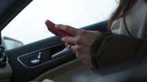 Woman texting on smartphone in car - close up on hands