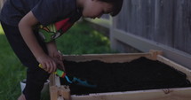 Young boy digging home garden- medium shot