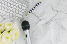 computer keyboard, roses, microphone, and pen on a marble background 