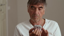Gray haired man using a cell phone.