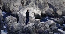 man standing on a mountainous rocky shore 