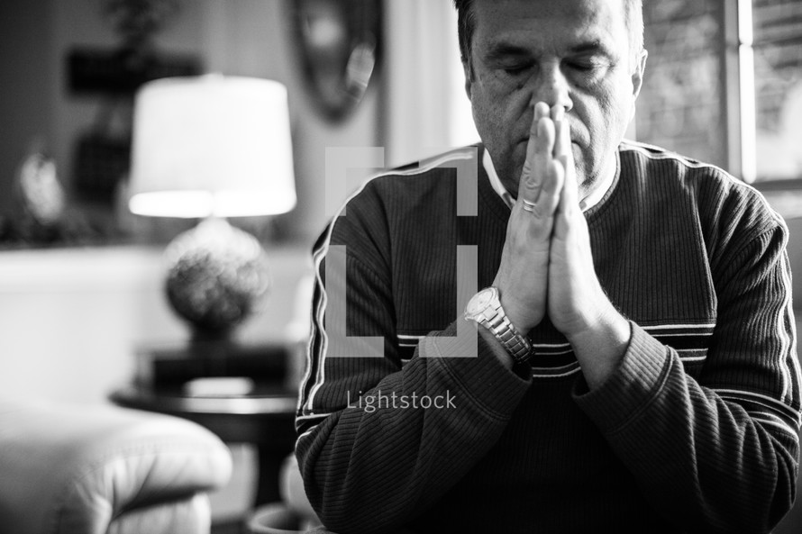 a man in a living room with praying hands 