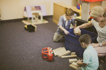 nursery staff and toddler boys playing with blocks 