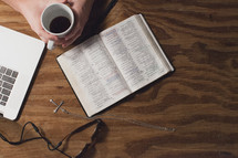 laptop, cross necklace, Bible, sunglasses, and coffee cup on a table 