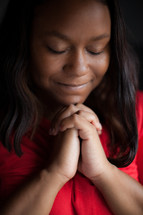 African-AMerican woman with head bowed and praying hands 