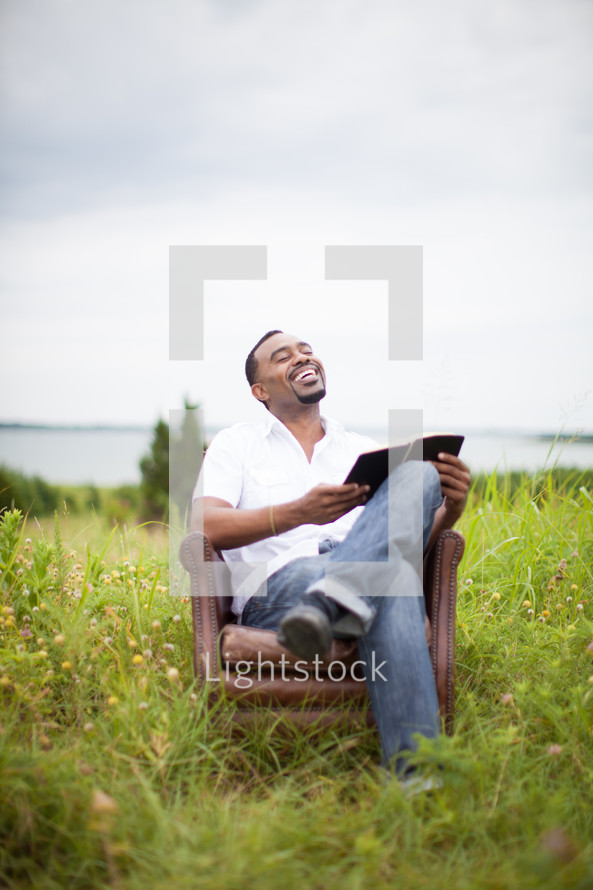 man reading a Bible in a chair outdoors 
