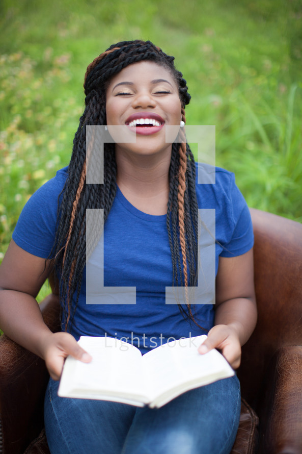 joyful woman reading a Bible outdoors 