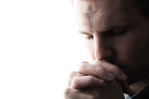 A man with ashes on his forehead in prayer for Ash Wednesday