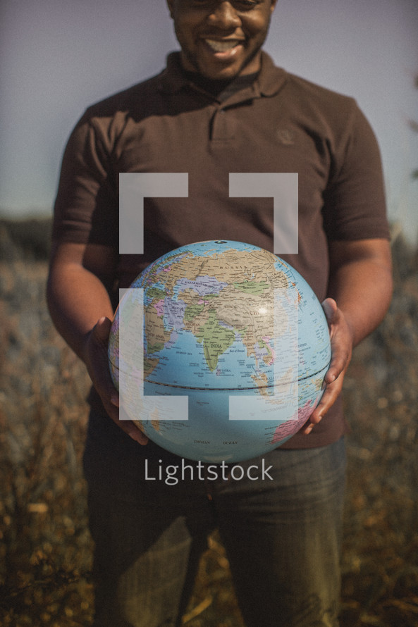 man holding a globe in a field 