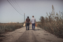 men walking down a dirt road with luggage 