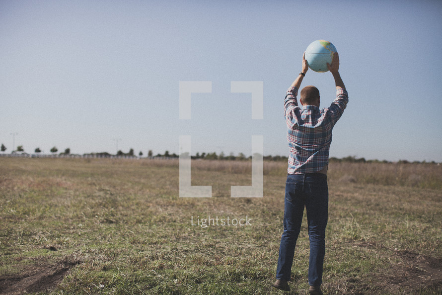 man in a field holding a globe 