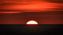 Wildfire smoke obscuring the sun at sunset over the ocean 