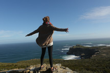 Woman standing on cliff overlooking ocean
