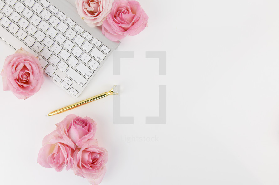 keyboard, pen, and roses on a desk 
