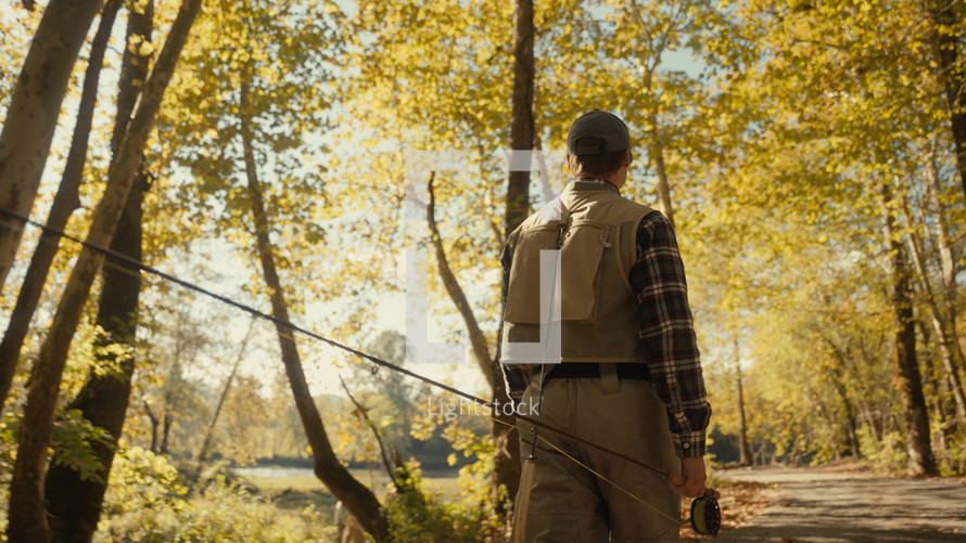 Young fly fisherman walking to a river at dawn