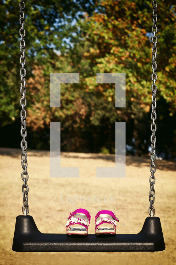 Pink sandals child on swing in the park