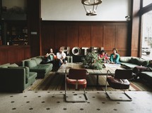 Four people sitting on couches in a hotel lobby.
