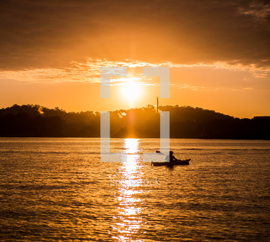 Silhouette of a rowboat in the water at sunset.