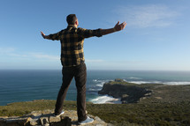 Man worshiping at the top of a cliff overlooking the ocean