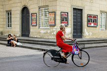 Elderly woman riding bicycle while smoking
