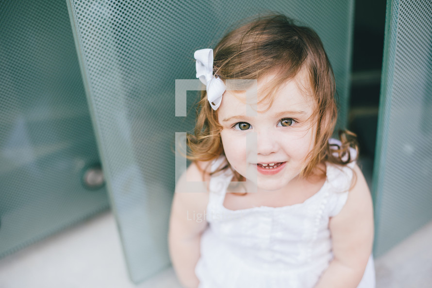 face of a little girl standing in front of a door 
