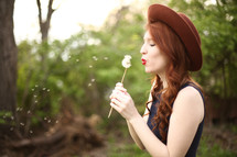 a woman blowing a dandelion 