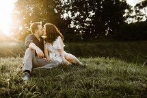 a couple sitting in the grass kissing 