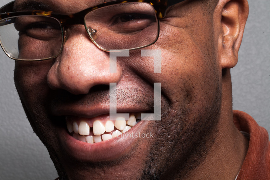 The face of a smiling man wearing glasses.