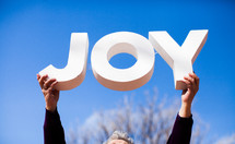 woman holding up the word JOY