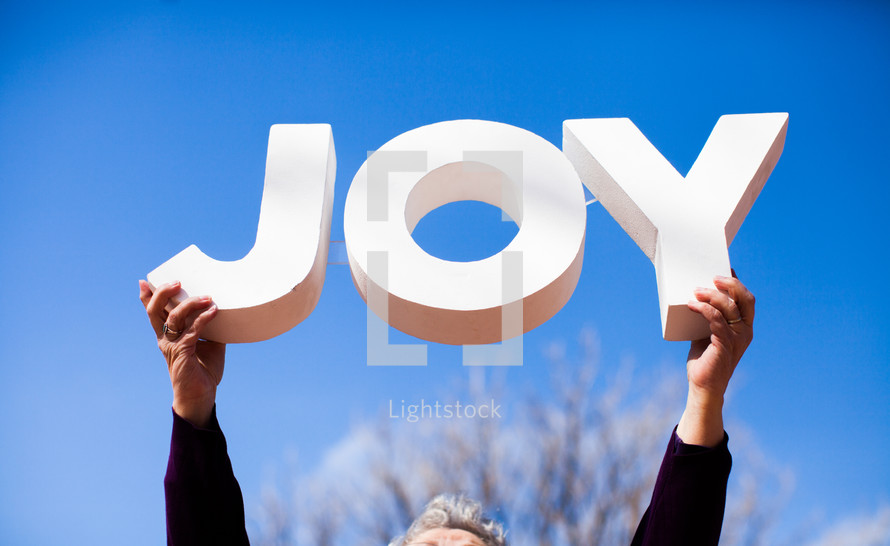 woman holding up the word JOY