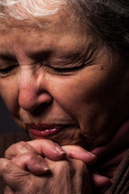 An older woman praying.