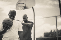 Men in prayer on a basketball court holding a basketball.