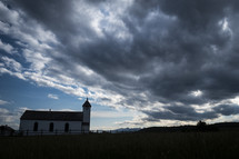 Small country church under approaching evening storm clouds
