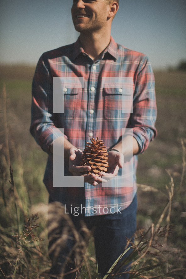 man holding a pinecone 