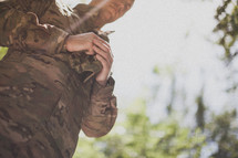 serviceman praying holding his hat