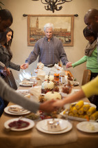 family holding hands in prayer at a Thanksgiving dinner table 
