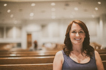woman smiling sitting in a church pew