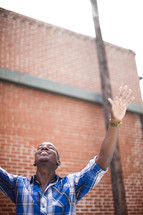 an African-American man with hands raised in worship 
