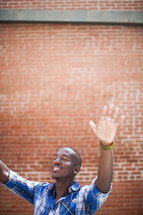 an African-American man with hands raised to God in worship 