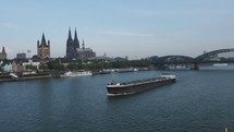 KOELN, GERMANY - CIRCA AUGUST 2019: Boat passing under Hohenzollernbruecke (meaning Hohenzollern Bridge) crossing the river Rhine - EDITORIAL USE ONLY