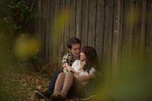 Couple hugging beside a wooden fence