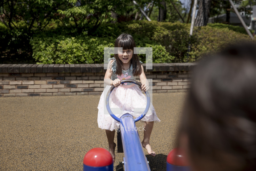 Little girl playing on seesaw