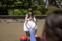 Little girl playing on seesaw