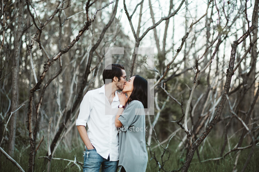 a couple kissing in the woods 