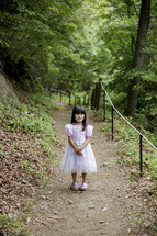 little girl in a dress on a dirt trail
